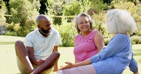 Enjoying Conversations Outdoors Seniors Sitting on Grass in Park