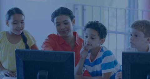 Female Instructor Guiding Schoolchildren Using Desktop Computers in Collaborative Classroom