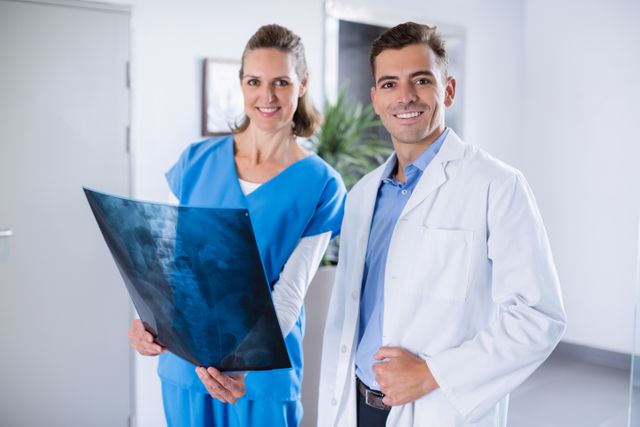 Portrait of two doctors standing with patients x-ray in hospital corridor