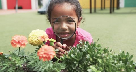 Curious Young Girl Exploring Flowers with Magnifying Glass in Playground