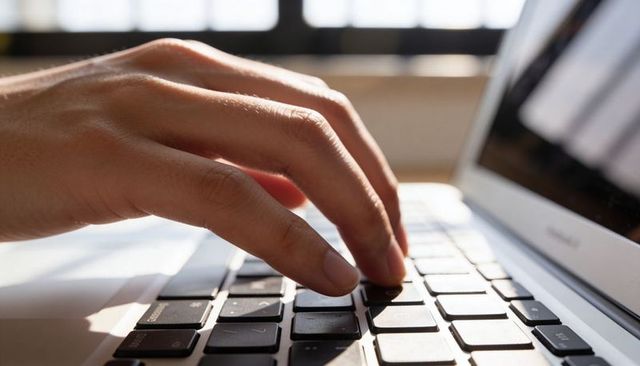 Backlit fingertips typing on laptop keyboard - close-up of right hand on chiclet keys