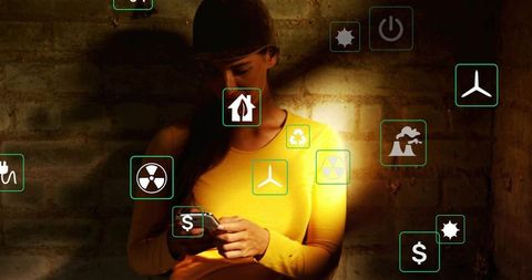 Tapping woman using smartphone with augmented reality energy icons in moody urban light