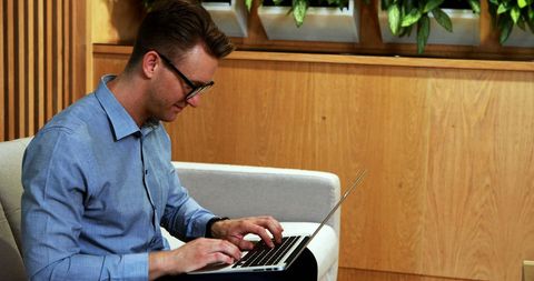Modern Businessman Focused on Laptop in Stylish Office Setting