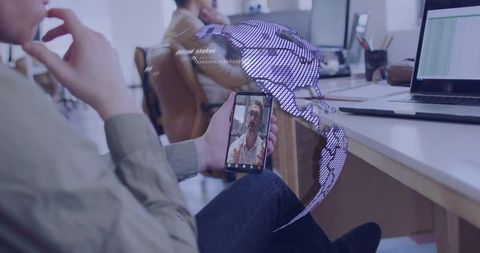 Remote collaboration via smartphone with holographic globe overlay in coworking workspace