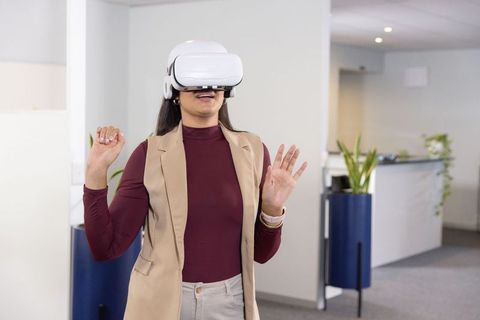 Businesswoman using vr headset and smartwatch experiencing virtual training in office