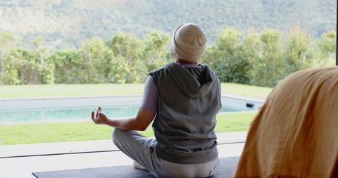 Mature Man Meditating on Poolside Patio with Scenic View