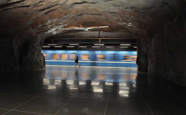 Person Walking Inside Rock-formed Subway Station with Passing Train - Download Free Stock Images Pikwizard.com