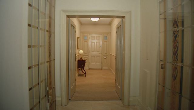 Framed double doors revealing elegant narrow entry hall with console table and lamp
