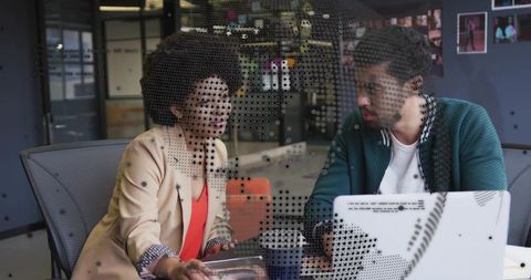 Colleagues collaborating through dotted glass partition in modern coworking workspace