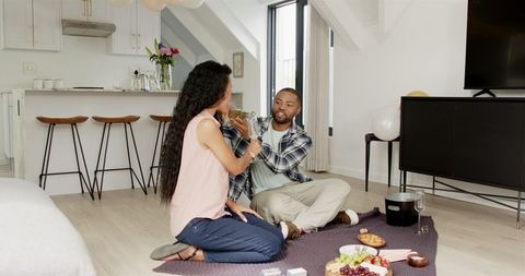 Romantic Indoor Picnic with Multiracial Couple Sharing Wine