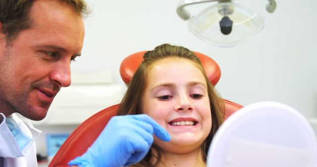 Dentist Checking Smiling Girl's Teeth in Dental Chair - Download Free Stock Images Pikwizard.com