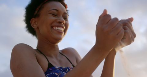 Smiling Woman Enjoying Warm Beach Sunset Playing with Sand