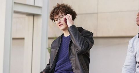 Two friends sitting on steps talking on phone in urban plaza casual street style