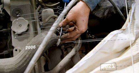 Greasy hand tightening hose clamp on dusty engine with timeline 2006-2021