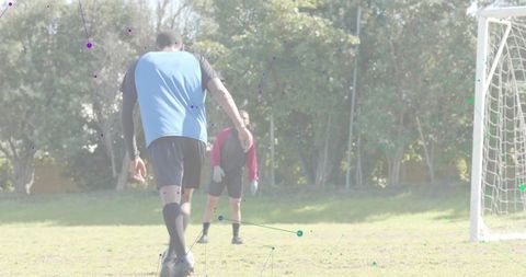 Soccer player approaching ball for penalty practice with goalkeeper watching on grass pitch