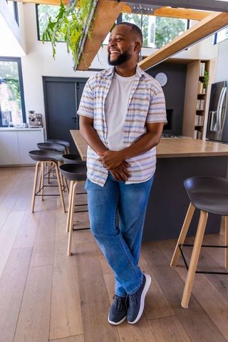 African american man smiling in modern sunlit kitchen, casual home lifestyle portrait