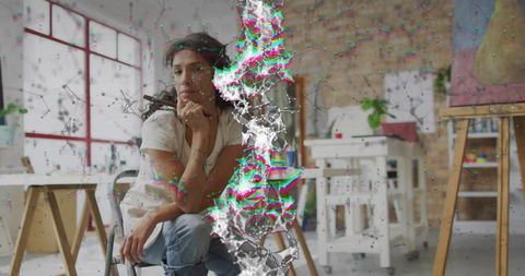 Contemplative artist resting chin in contemporary studio with abstract digital glitch