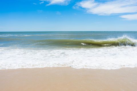 Ocean Waves Crashing on Sandy Beach Under Clear Blue Sky, Calm Seascape Horizon