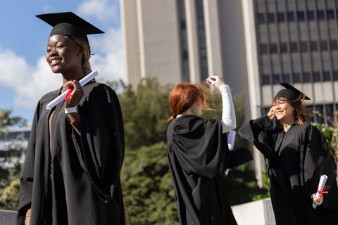Graduating together celebrating diverse women in caps and gowns on university campus