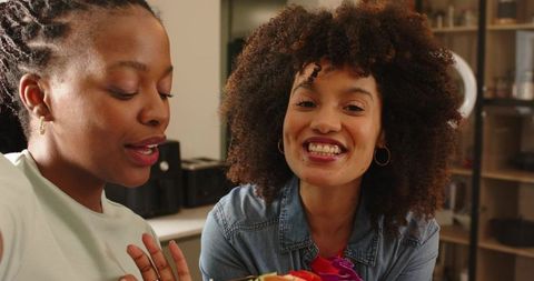 Two friends chatting and crafting colorful ribbon flowers at cozy kitchen counter
