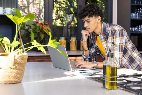 Young Man Using Laptop in Modern Kitchen Island Workspace