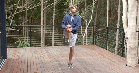 Young African American Man Stretching Outdoors on Sunny Deck