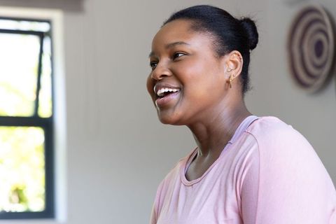 Smiling african american woman talking in soft daylight indoors wearing casual pink top