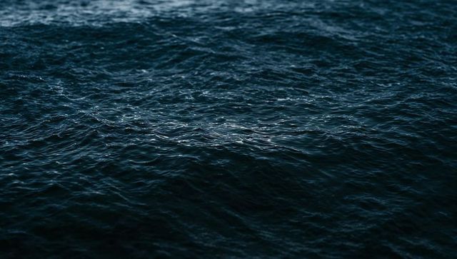 Dark rippling ocean surface with subtle highlights and textured wavelets