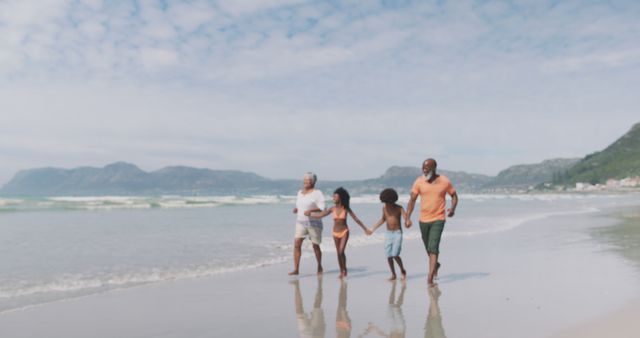 Biracial senior couple with grandchildren walking and holding hands at the beach. healthy outdoor leisure time by the sea.