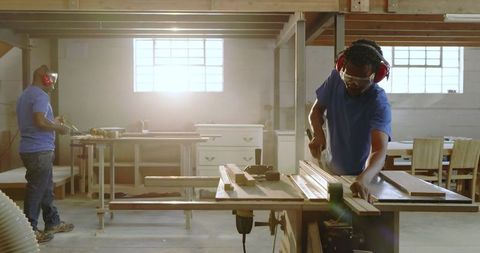 Craftsmen working in wood workshop with safety gear