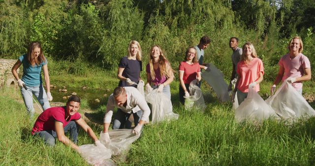 A multi-ethnic group of happy conservation volunteers cleaning up a river on a sunny day in the countryside, picking up rubbish. Ecology and social responsibility in a rural environment.