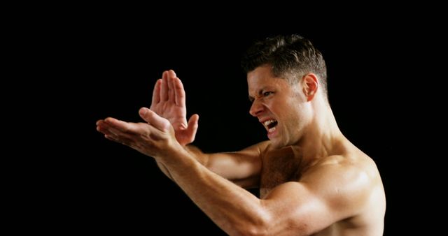 This image shows a man practicing martial arts while shouting, demonstrating intense focus and strength. It is useful for articles about fitness, self-defense, martial arts training guides, and advertisements for sports equipment or fitness programs.