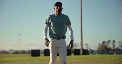Baseball player standing on sunlit field preparing for practice and training