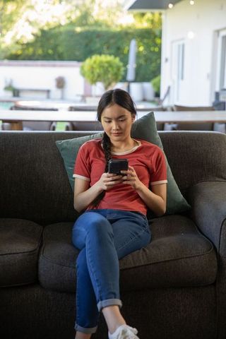 Young Woman Relaxing Outdoors with Smartphone in Cozy Setting