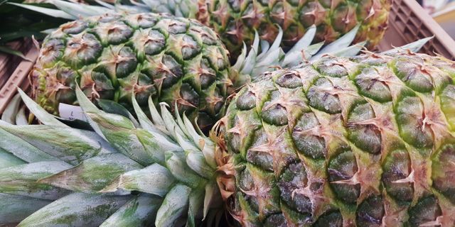 Consists of several ripe pineapples arranged closely together, likely in a market or grocery setting. Ideal for use in food and beverage advertisements, healthy eating promotions, grocery store marketing materials, and content focused on tropical fruits or exotic produce.