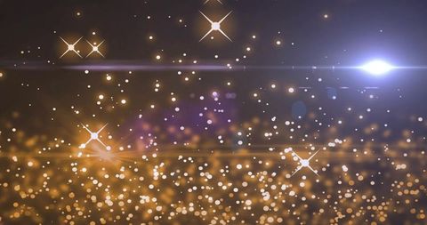Glittering golden bokeh with starbursts and blue lens flare for festive abstract background