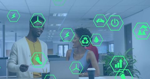 Colleagues collaborating at laptop in open office with green sustainability tech icons