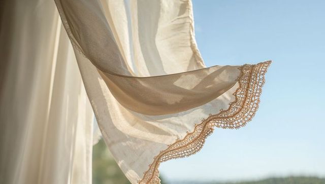 Billowing sheer curtain with scalloped lace trim catching sunlight and soft coastal breeze