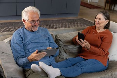 Senior Couple Relaxing on Sofa with Digital Devices