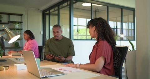African american colleagues collaborating over tablet and charts in modern open-plan office