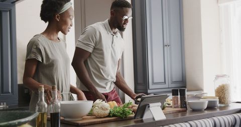 Couple preparing meal with tablet in kitchen