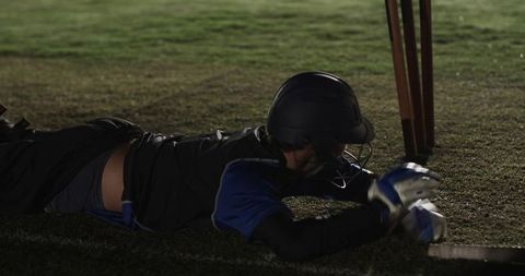 Diving cricketer reaching crease under floodlights wearing helmet gloves and bat action