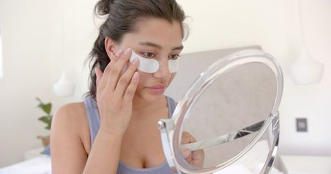 Teen Applying Under Eye Masks for Skincare in Mirror