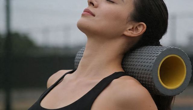 Woman using textured foam roller for neck relief and mobility during outdoor recovery