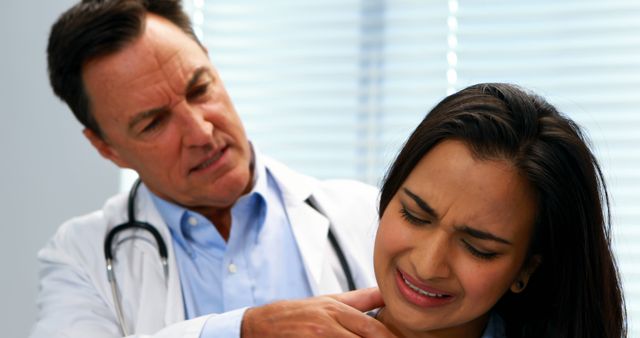 A middle-aged Caucasian male doctor examines the shoulder of a young Hispanic female patient, expressing discomfort, with copy space. His concern reflects the professional care provided in medical consultations, while her reaction underscores the importance of addressing pain promptly.