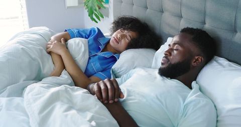 Couple sleeping peacefully side by side in sunlit bed, cozy morning intimacy and relaxation