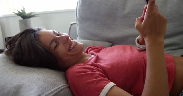 Young Woman Smiling while Using Smartphone on Couch - Download Free Stock Images Pikwizard.com