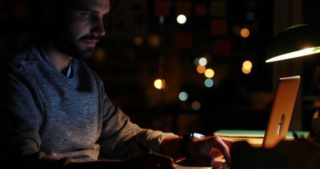 Focused man working late on laptop in dimly lit office - Download Free Stock Images Pikwizard.com