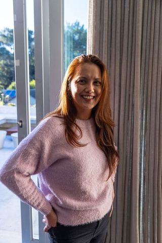Smiling Woman in Pink Sweater by Glass Doors with Curtains