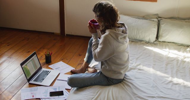 Young Woman Working from Bed with Laptop and Documents - Download Free Stock Images Pikwizard.com